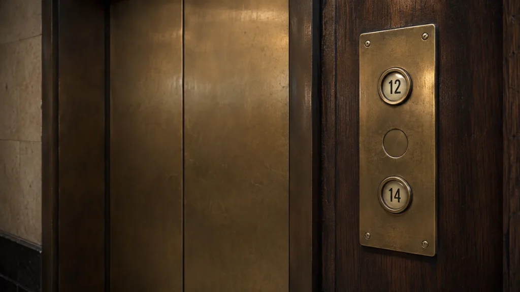 Old brass lift panel showing buttons 12 and 14 with the thirteenth-floor position deliberately left blank.